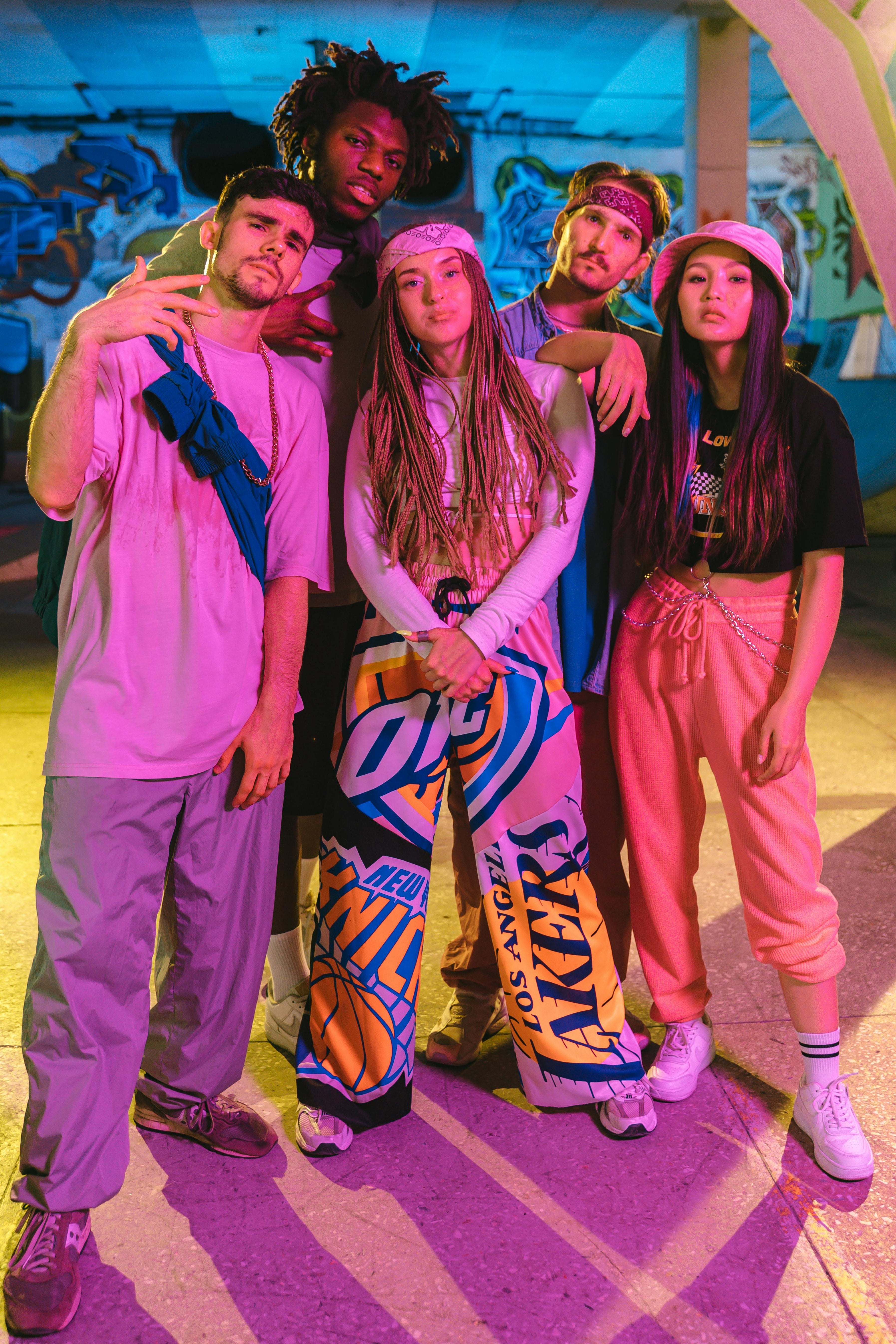 Group of five people posing together in a colorful indoor setting.